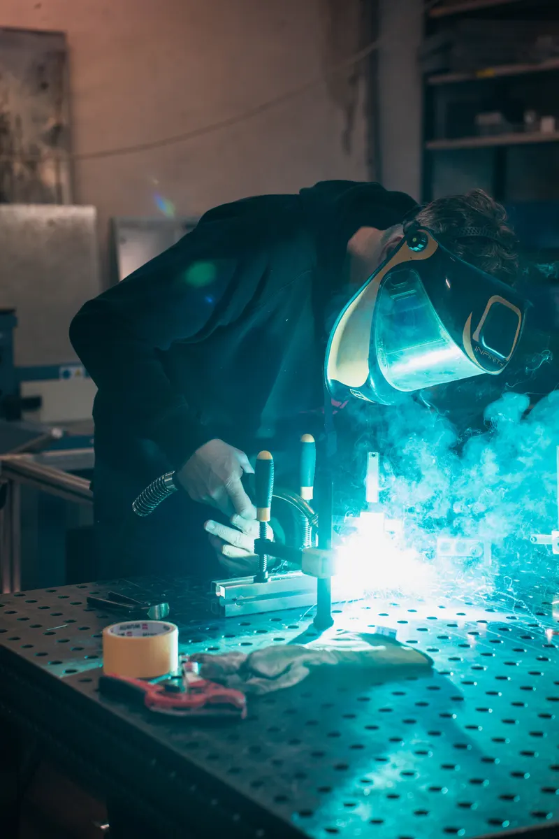 Saldatore al lavoro in officina, fotografia industriale di Team247 per un'azienda in Alto Adige