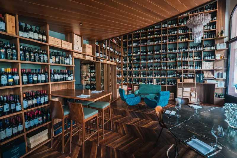 Enoteca con parete di vini e sala degustazione, fotografia di Team247